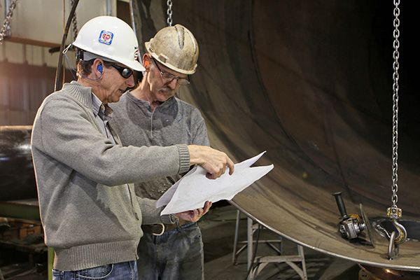 Two Men looking over plans at a construction site with protective earmolds in their ears - El Paso TX