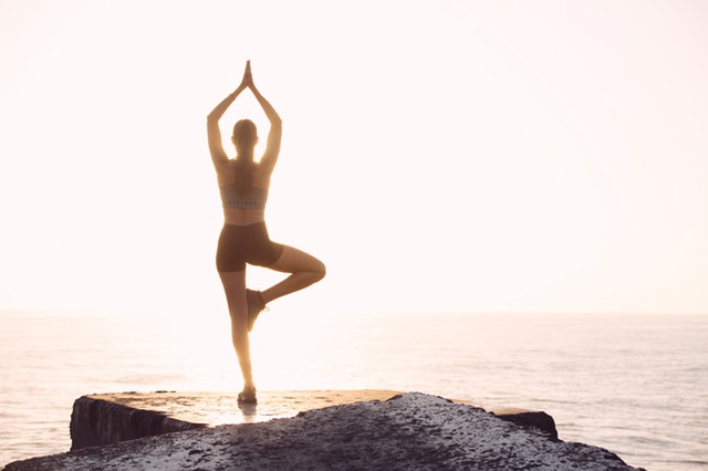 person doing yoga on a cliff