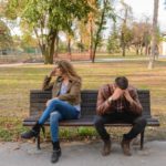 couple in a fight sitting on a park bench