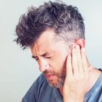 Man with earache is holding his aching ear body pain concept