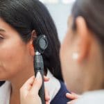 Woman receiving an ear exam by an audiologist