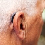 Close up of a man wearing a behind-the-ear hearing aid.