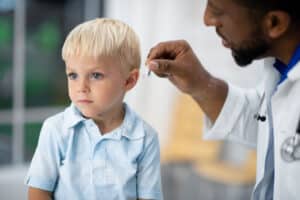 Young boy being fitted with hearing aids by an audiologist.