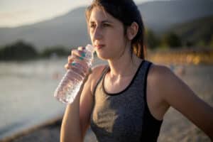 Woman wearing hearing aid on a run drinking out of a bottle