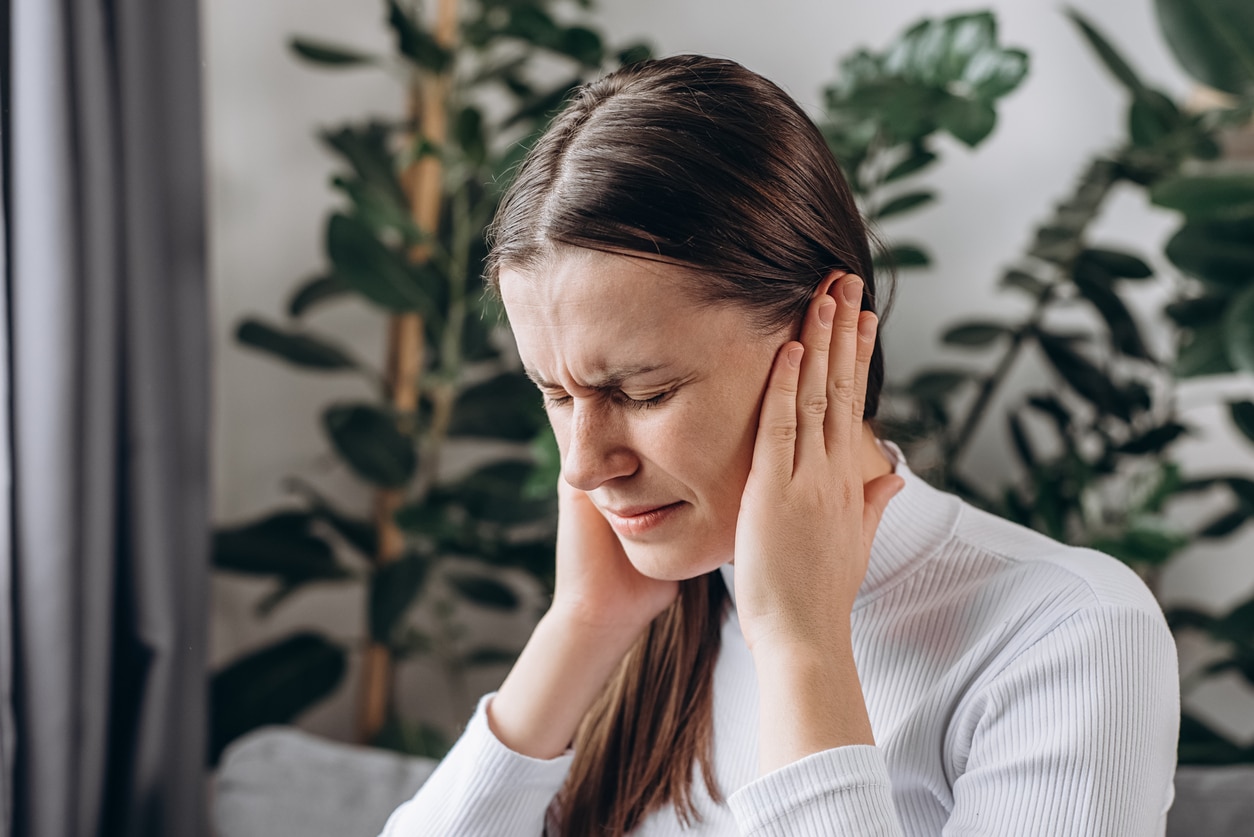 Woman holding her ears to block out tinnitus.