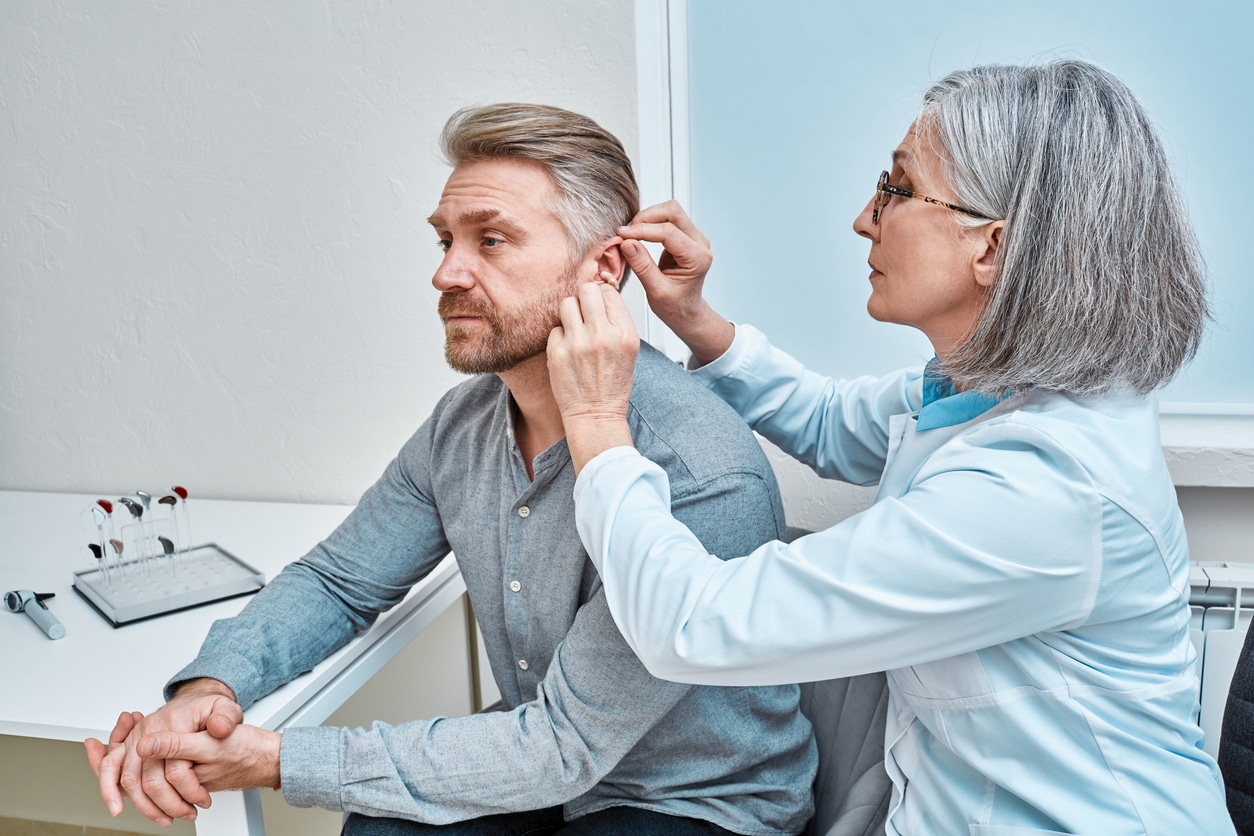 Audiologist fitting a man for a new hearing aid